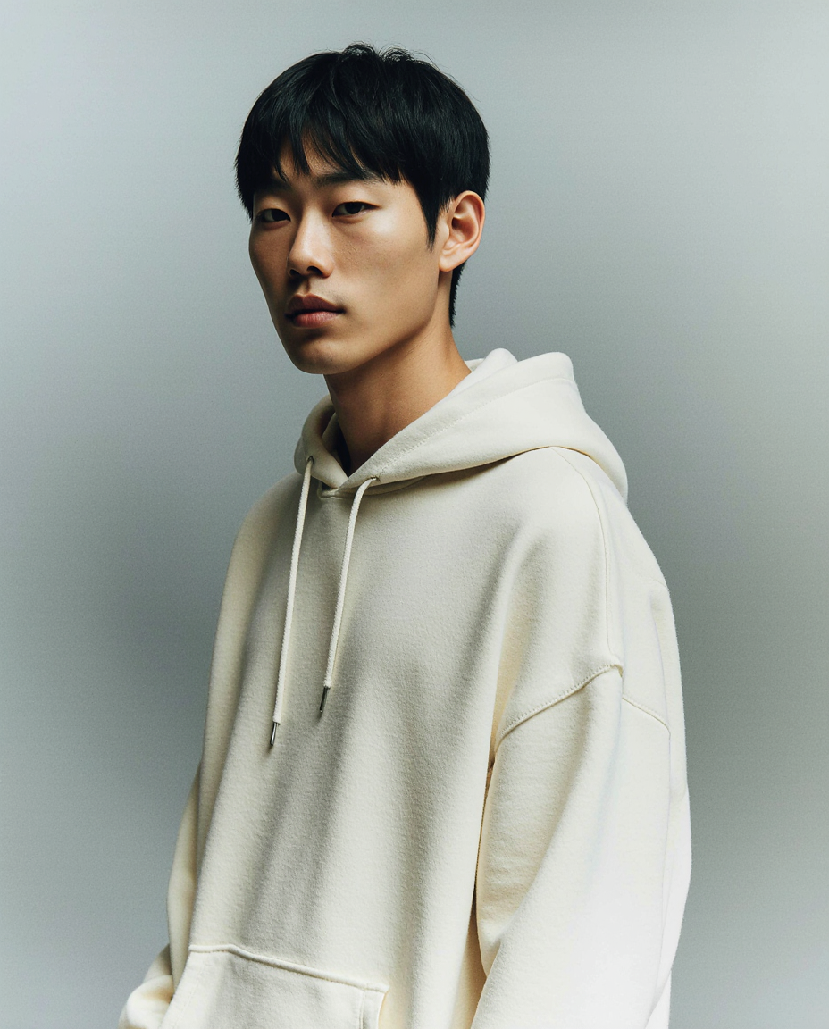 Person wearing a beige hoodie against a gray background